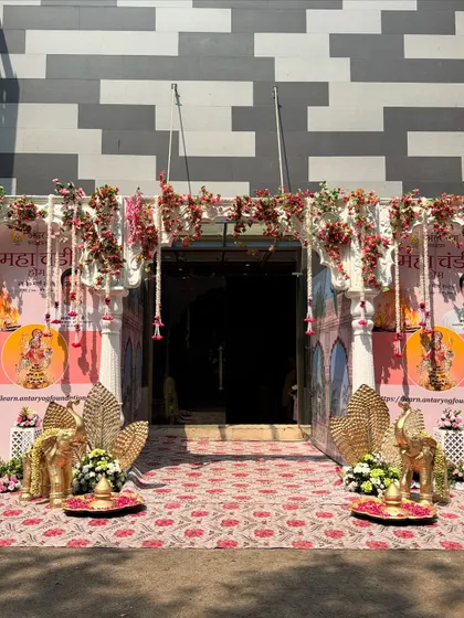 A full view of the entrance for a Maha Navami celebration, featuring floral arches, golden elephants, and traditional motifs. The design is grand yet respectful, creating a welcoming space for devotees.