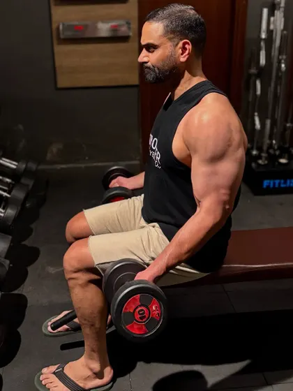 Another angle of a seated dumbbell curl, an exercise used to supplement the main compound lifts and build arm strength for grappling.