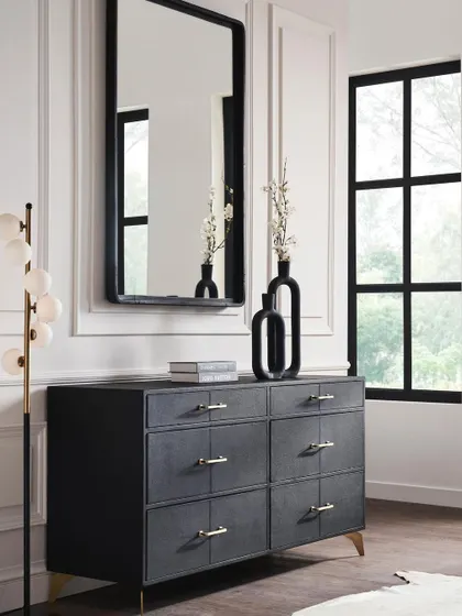 The six-drawer dresser from the black collection, styled with a matching mirror and modern decor. The composition is clean and elegant, focusing on the product's sophisticated lines.