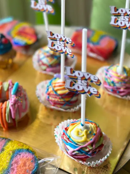 We celebrate love in all its forms. Our Pride Month collection features colorful treats like these rainbow cake pops with 'Love is Love' flags.