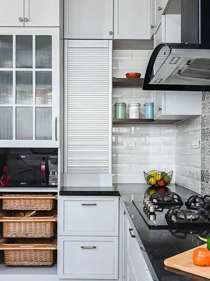 A detail shot of the classic grey kitchen, showing the wicker baskets for vegetable storage and the fluted glass cabinet for display. The patterned backsplash adds a touch of personality.
