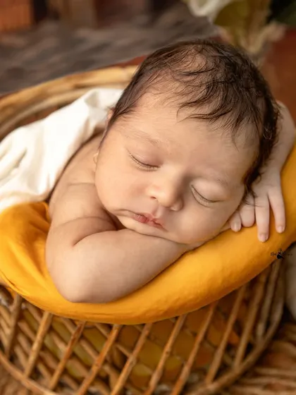 The classic 'chin on hands' pose, perfect for showing off a newborn's sweet, sleepy face. This pose is always done safely with composite images to ensure the baby is supported.