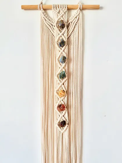 This custom wall hanging incorporates seven different stones, each representing one of the chakras. It's a meaningful piece designed to bring balance and positive energy into the home.