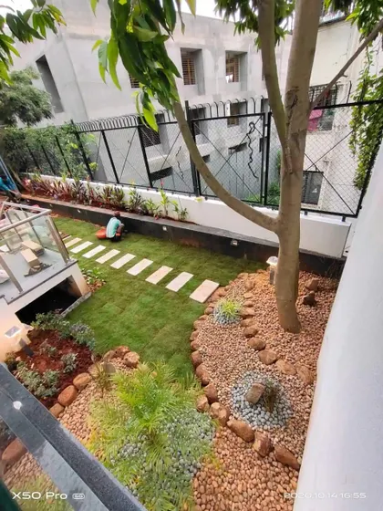 An elevated view of a modern garden design, featuring a central lawn area, a stone pathway, and beds filled with pebbles and rocks. This shows my work in creating multi-textured landscapes.