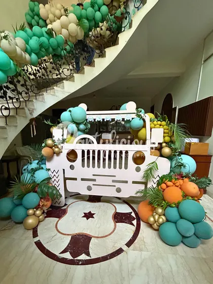 A safari jeep prop, decorated with colorful balloons, serves as a fantastic photo booth and centerpiece for a jungle-themed party.