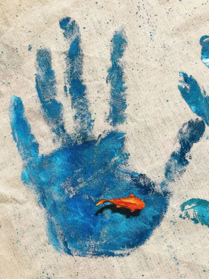 A simple handprint on a tote bag, with a tiny fish painted in the palm. It's a small piece with a big message about our impact on the oceans.
