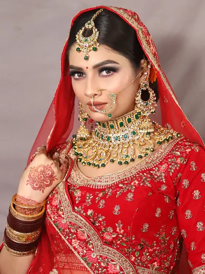 A powerful and regal bridal look. The focus here is on the intense smokey eye and the perfectly sculpted brows, paired with heavy kundan and emerald jewelry for a truly royal wedding day appearance.