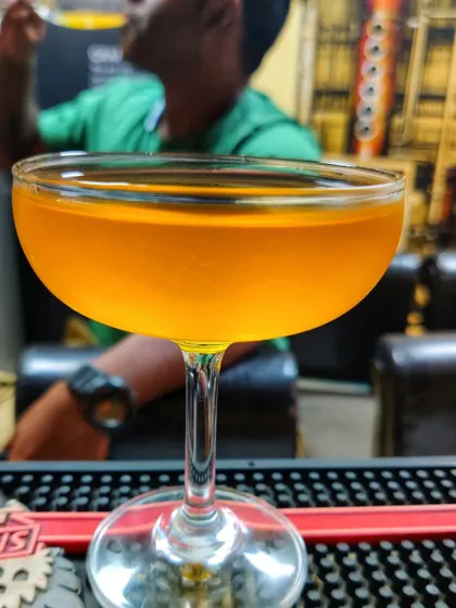 A classic coupe glass holding a golden-hued cocktail, enjoyed at the bar. This image captures the simple pleasure of a well made drink at the end of the day.