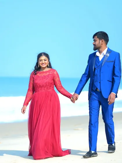 A happy couple enjoying a walk on the beach. The bright red gown and electric blue suit make for a vibrant and cheerful pre-wedding photo.