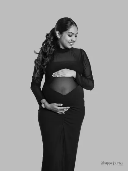 A classic black and white portrait. The simple elegance of this sheer black gown and the soft lighting create a timeless and sophisticated image that focuses on the beauty of the mother-to-be.