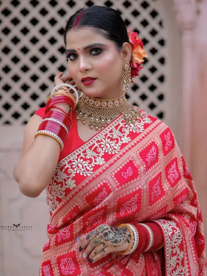 A close-up portrait focusing on the intricate patterns of the saree and the beautiful henna design on her hand.