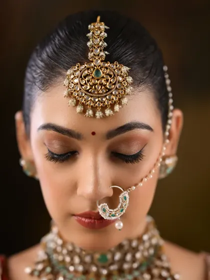 A downward glance showcasing the flawless eyeshadow blending and the intricate maang tikka.