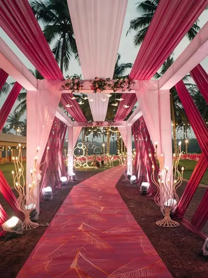 A dramatic and modern entrance walkway with crisscrossing pink and white drapes.