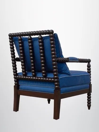 The back of the spindle chair shows the intricate woodwork and the comfortable, plush back cushion.