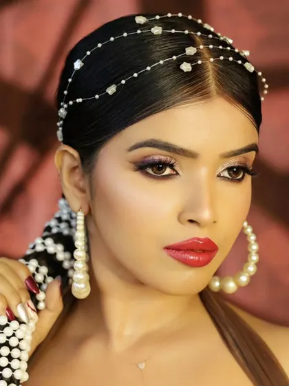 A portrait that showcases the entire headpiece and pearl-decorated braid, along with large hoop earrings. It’s a complete, high-fashion beauty look.