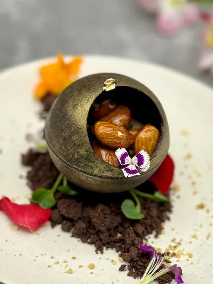 Another view of our Caramelised Chocolate Mousse Sphere, highlighting the edible flowers and rich chocolate soil that complete this artistic and delicious creation.