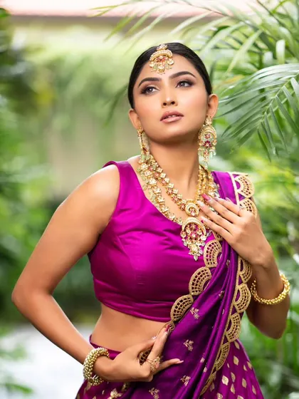 This portrait captures the rich color of the purple sleeveless blouse and the intricate details of the matching jewelry set, showing a complete and polished look.