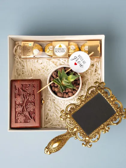 Inside the naming ceremony return gift box, you'll find a succulent plant with a 'Watch Me Grow' tag, a carved wooden box, and an antique-style hand mirror.