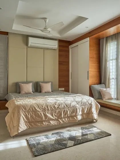 A bedroom in the 'Wilasa' villa, designed for comfort and style. It features a cushioned headboard, a cozy window seat for reading, and a neutral color palette that promotes restfulness.
