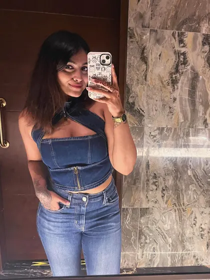 A mirror selfie in a full denim look. This trendy outfit features a denim halter top with a zip detail and matching high-waisted jeans.