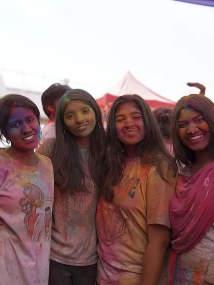 A group of friends smiling for the camera, covered in Holi colors. We love capturing the happy faces at our events.