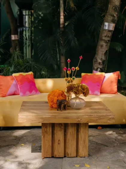 A comfortable lounge area for the Mehendi, with a yellow sofa and bright pink and orange cushions.