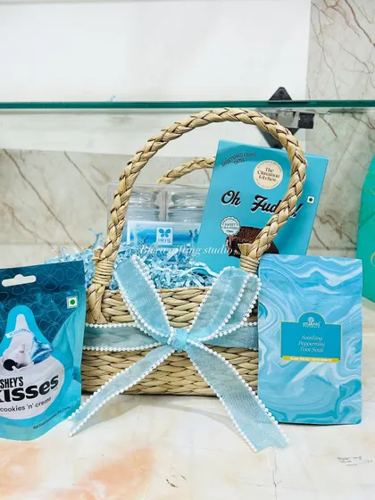 The new mom hamper, perfectly assembled with blue paper shred, Hershey's Kisses, fudge, and skincare, ready to be gifted.