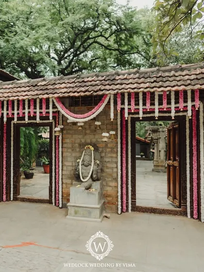 The entrance to a wedding ceremony, decorated with traditional pink and white floral garlands. The simple yet elegant design sets a welcoming and sacred tone for the event.