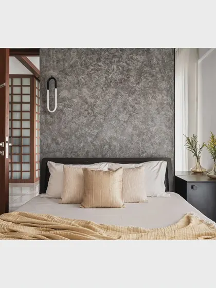 The master bedroom in the 'Nordic Grey Apartment' features a concrete-textured accent wall behind the bed, creating a grounding and minimalist backdrop.