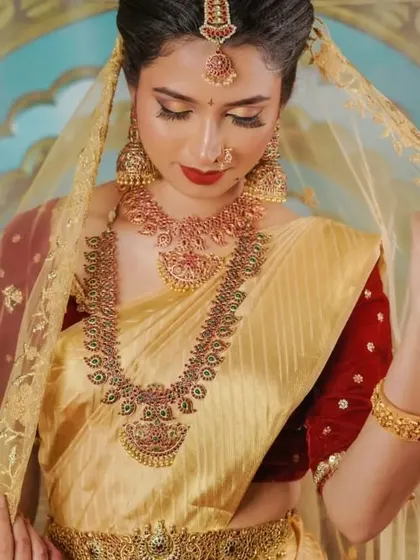 The sheer golden veil adds a touch of royal elegance to this traditional look. The makeup remains classic and timeless, allowing the beautiful jewellery and outfit to shine.