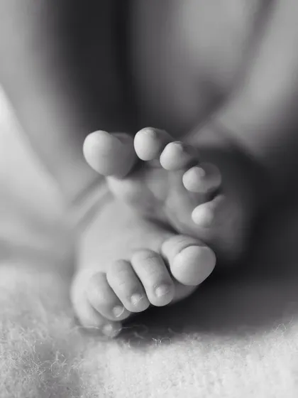 A macro shot of a newborn's crossed feet, showing every perfect little wrinkle and toe. These are the details that truly matter.