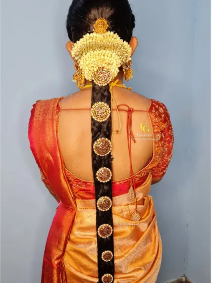 A hairstyle is just as important as the makeup. Here is a traditional South Indian bridal braid, intricately woven and adorned with fresh jasmine flowers (gajra) and classic temple jewelry hair accessories.