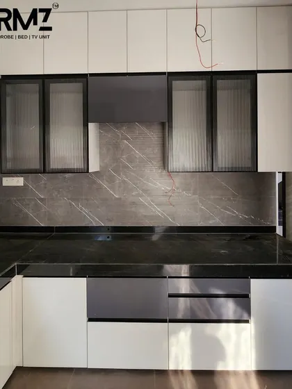 This image shows a combination of white gloss cabinets and fluted glass shutters with a dark profile. The grey marble-effect backsplash adds a sophisticated, natural texture to the modern design.