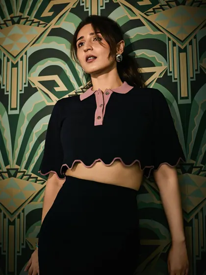 This pose shows off the scalloped hem of the crop top and the flattering fit of the matching skirt.