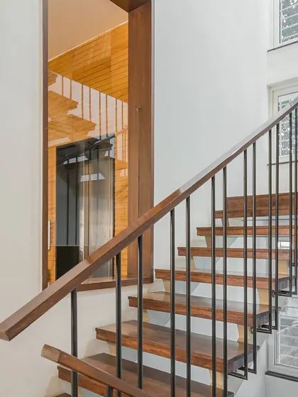The staircase in this residence is designed with clean lines, using a combination of warm wood for the steps and sleek metal for the balustrade. It serves as a functional element that is also a key part of the home's modern aesthetic.
