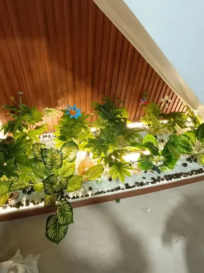 This under-stair garden features a mix of white and black pebbles, along with some colorful artificial flowers for an extra decorative touch.