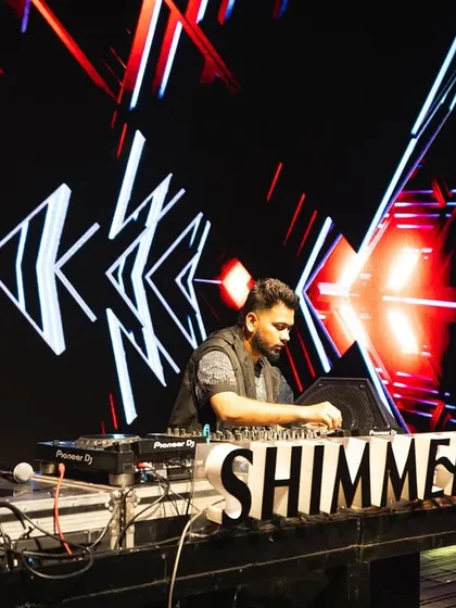 At the decks at Shimmers, with my custom visuals and the club's branding creating a high-impact stage presence.