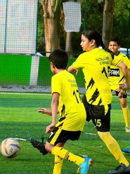 A female player competes for the ball, showing strength and determination. I empower all my players to be assertive on the field.