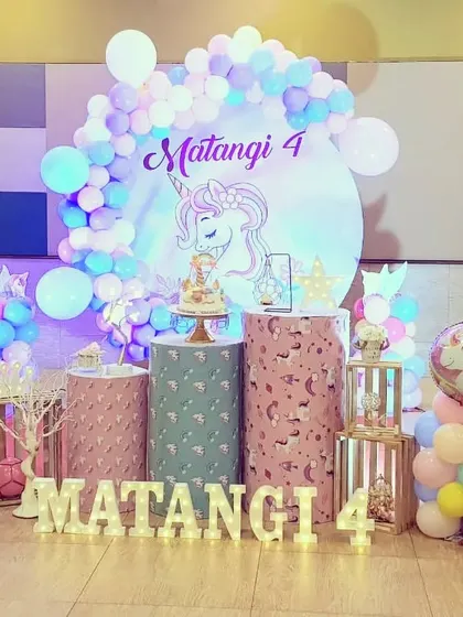 A full view of our unicorn theme decor. The setup features a custom backdrop, printed pedestals for the cake and desserts, and balloon arrangements in dreamy pastel colors.