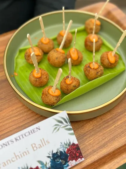 A platter of my Arancini Balls, which are crispy fried risotto balls with a gooey cheese center. They are served with a flavorful dip and are always a hit with guests.