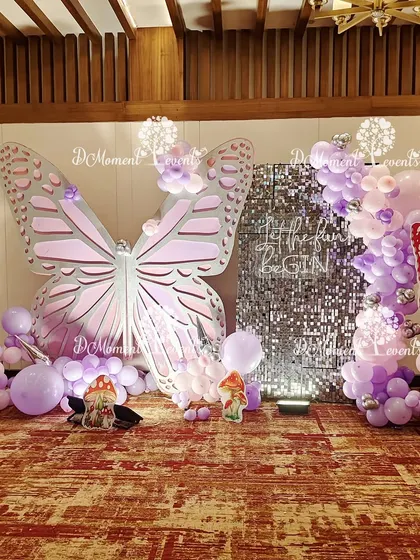 A full view of the fairy and butterfly photo booth, showing the scale of the butterfly prop and the beautiful lavender and pink balloon garland.