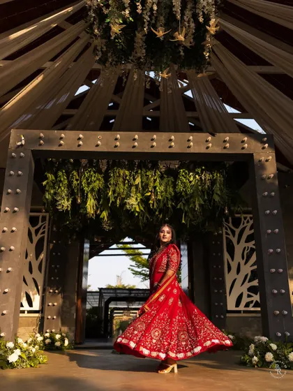 The bride twirls in her vibrant red lehenga at the entrance of the venue, a perfect shot to capture the grandeur of the Sangeet night.