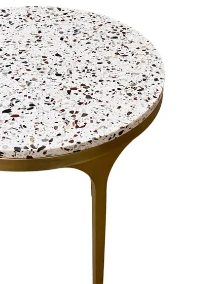 A close-up of the 'Tyra' side table's terrazzo top. The pattern of the stone chips adds visual interest while maintaining a light and airy feel.