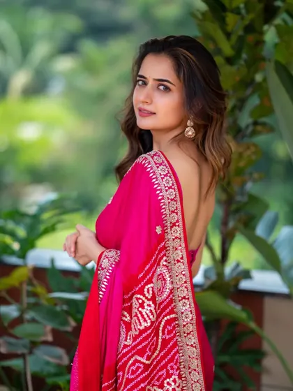 A full-length shot of Ashika Ranganath, showing how the saree drapes against the natural backdrop. This type of shot is great for showing both the outfit and the personality.