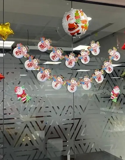 Simple Christmas decorations for an office glass wall, using festive banners and star shaped foil balloons.