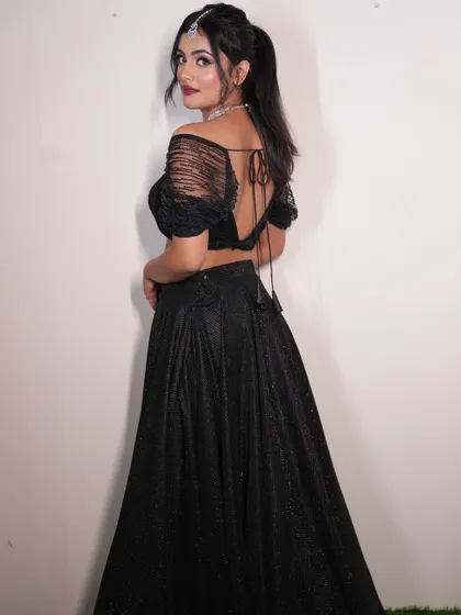 The back view of this chic black shimmer lehenga shows off its modern design with a tie-up detail. The sheer, embellished sleeves add a touch of glamour.