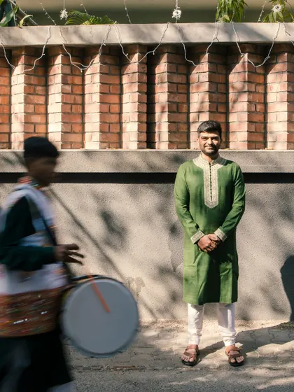 A candid shot of the groom in a striking green kurta, a modern and refreshing choice for a pre-wedding event.