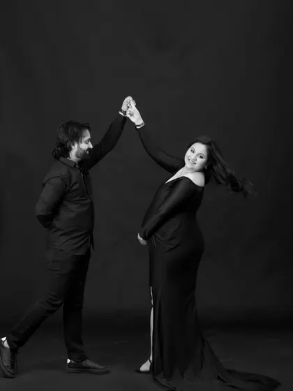 A fun and dynamic black and white studio shot. The couple shares a dance, capturing a moment of joy and movement during their maternity session.