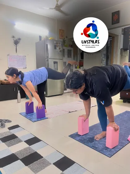 Two clients practice Warrior III with blocks, a balance pose that strengthens the entire body.