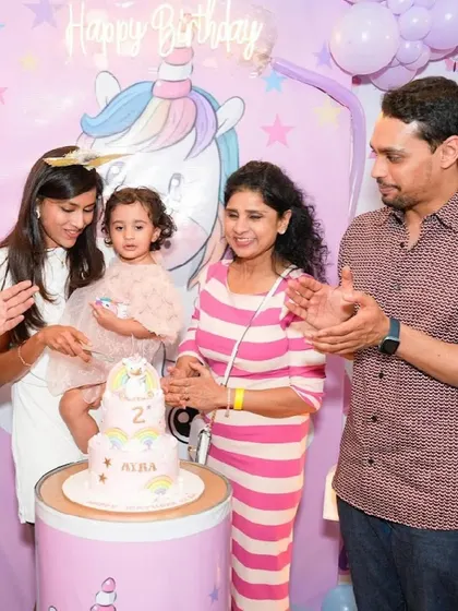 A family celebrates their daughter's 2nd birthday with a unicorn-themed cake and party.
